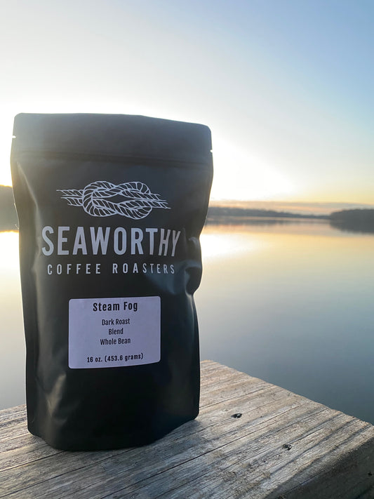 Seaworthy slow roasted, small batch, low acid coffee. 1 pound bag of Steam Fog dark roast specialty coffee.  Bag of coffee on dock on Narrow River in Rhode Island.  Steam Fog on water.  